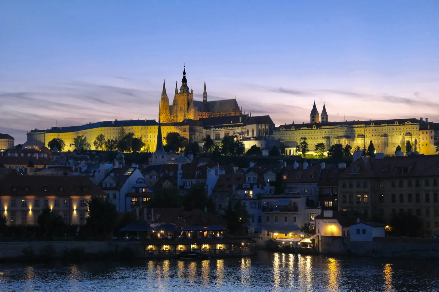 Prager Burg und Kleinseite am Abend, beleuchtet über der Moldau