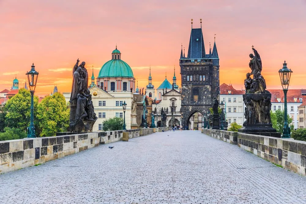 Altstädter Brückenturm am Ende der Karlsbrücke mit barocken Statuen und Laternen bei Sonnenaufgang