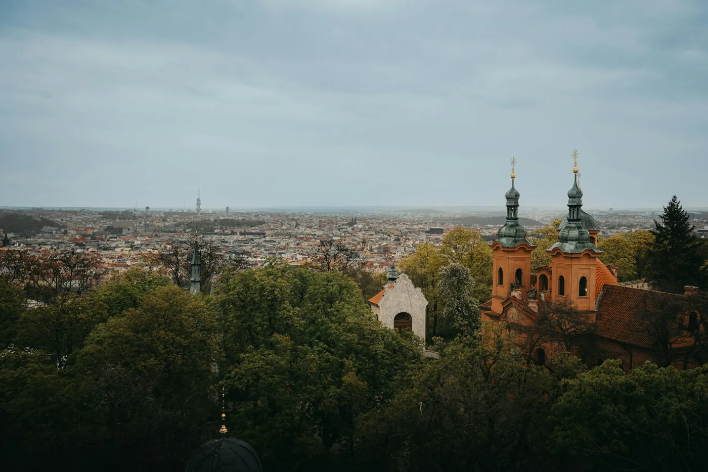 Blick vom Petřín über die Laurentiuskirche mit ihren zwei Türmen auf Prag, am Horizont der Fernsehturm Žižkov