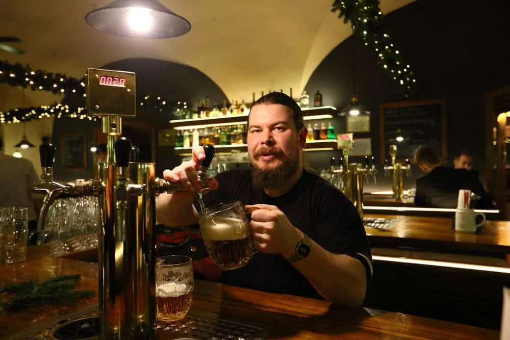 Zapfer mit Bierkrug an einem goldenen Zapfhahn in einem Prager Lokal