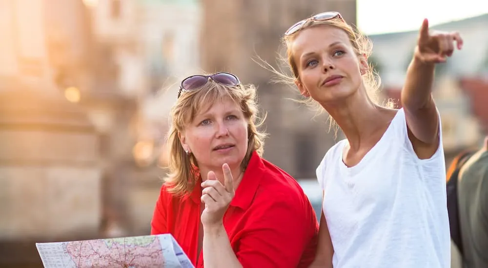 Zwei Frauen mit Stadtplan zeigen auf eine Sehenswürdigkeit in Prag