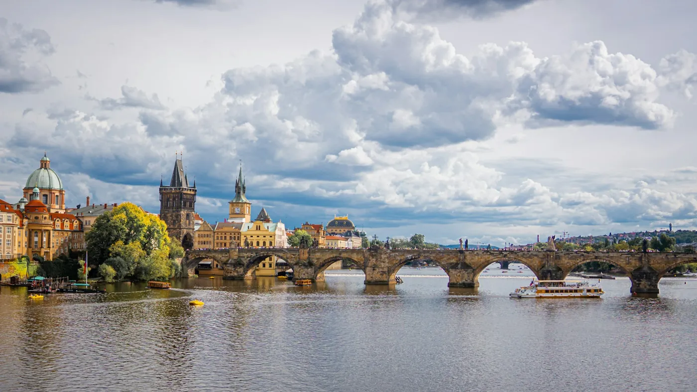 Karlsbrücke über die Moldau mit Altstädter Brückenturm und der Kuppel der Kreuzherrenkirche unter Wolken