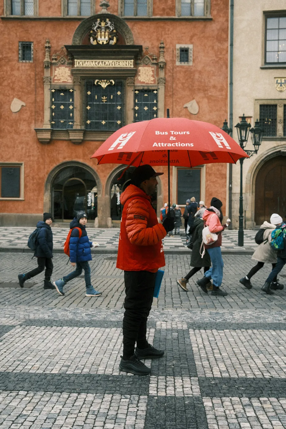 Mann mit rotem Werbeschirm für Bustouren vor dem Altstädter Rathaus in Prag