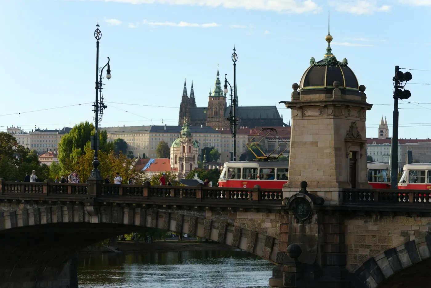 Rote Straßenbahnen auf der Legionenbrücke in Prag, dahinter die Prager Burg mit dem Veitsdom