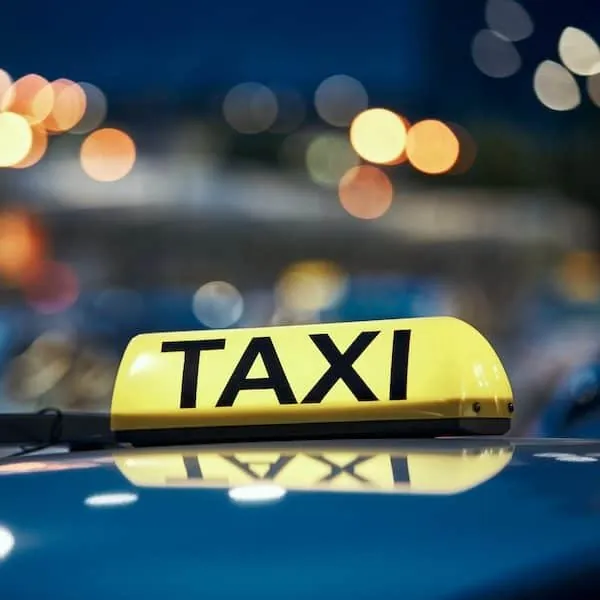 Gelbes Taxischild auf einem Autodach bei Nacht