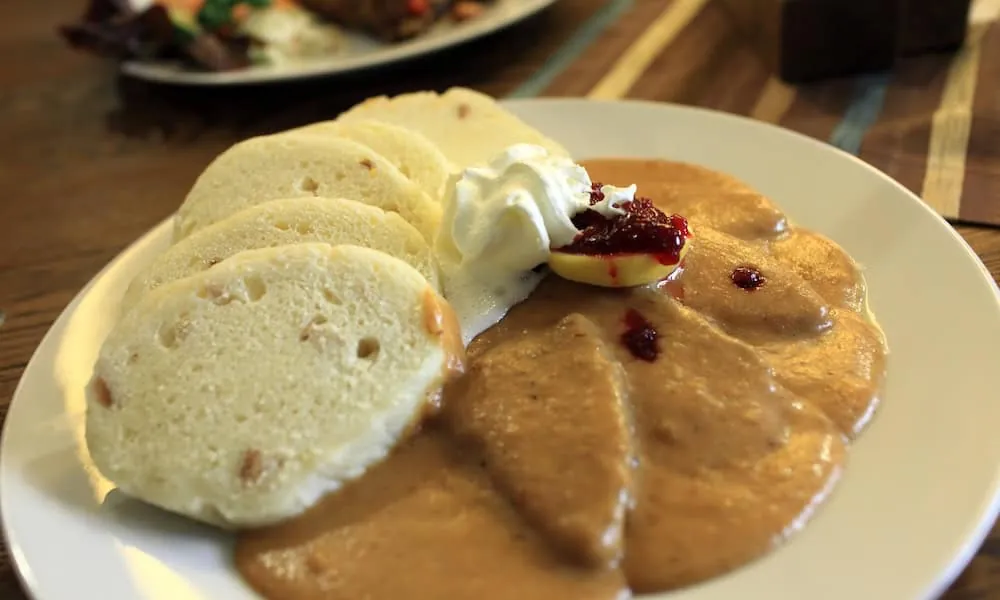 Svíčková mit Semmelknödeln, Sahnesoße, Preiselbeeren, Zitrone und Sahnehaube