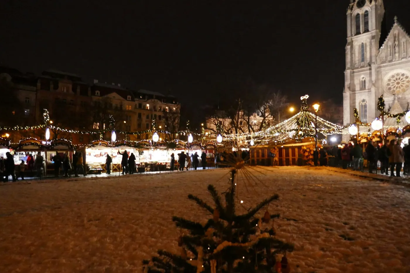 Weihnachtsmarkt am Náměstí Míru bei Nacht mit beleuchteten Ständen, Schnee und der Ludmilakirche